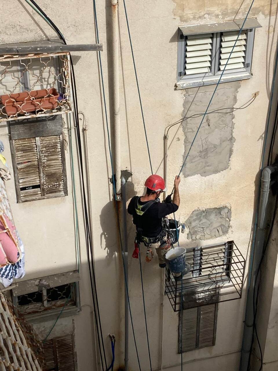 צוות גולשים מבצע עבודות גובה בסנפלינג על חזית בניין