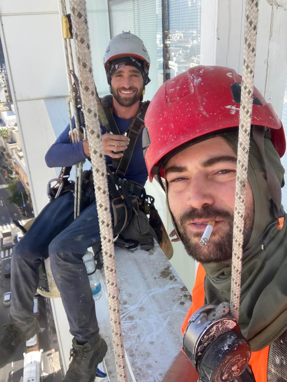 עובד סנפלינג מתקן מרזב בקומה עליונה של בניין מגורים