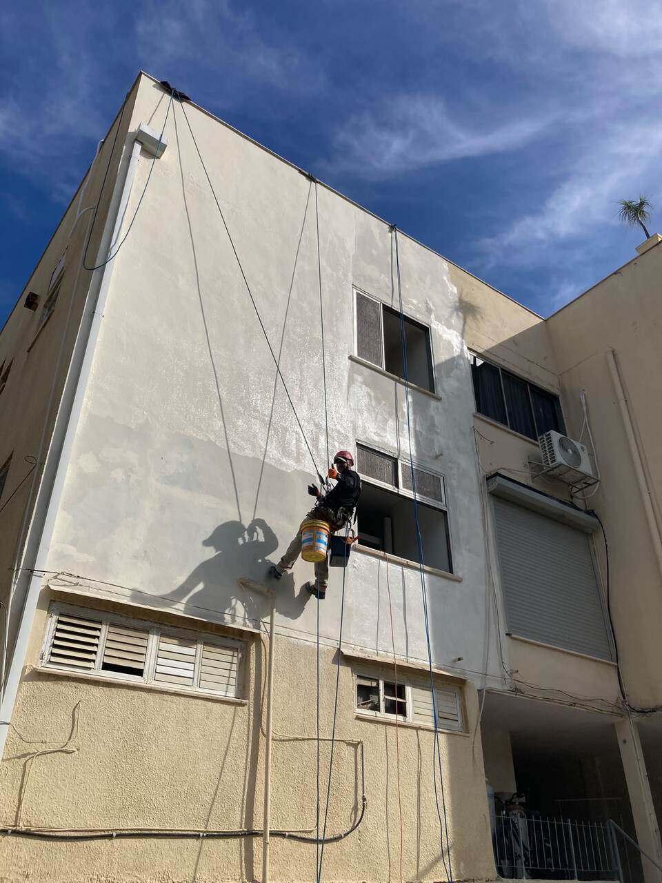 עובד מבצע חיזוק אבן בקיר חיצוני בגישת סנפלינג
